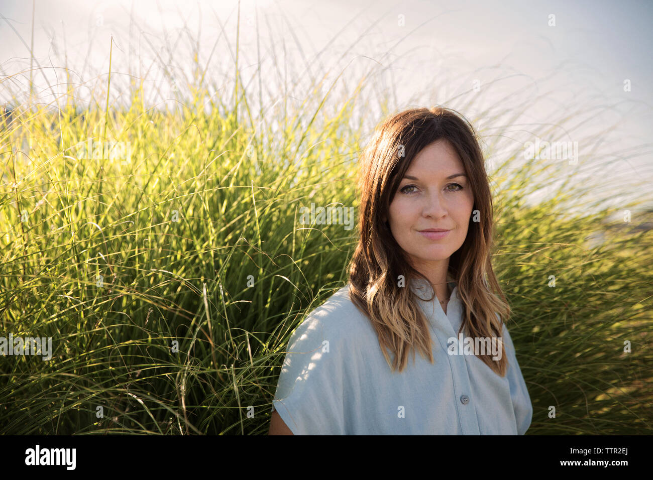 Ritratto di bella donna contro erba sulla giornata di sole Foto Stock