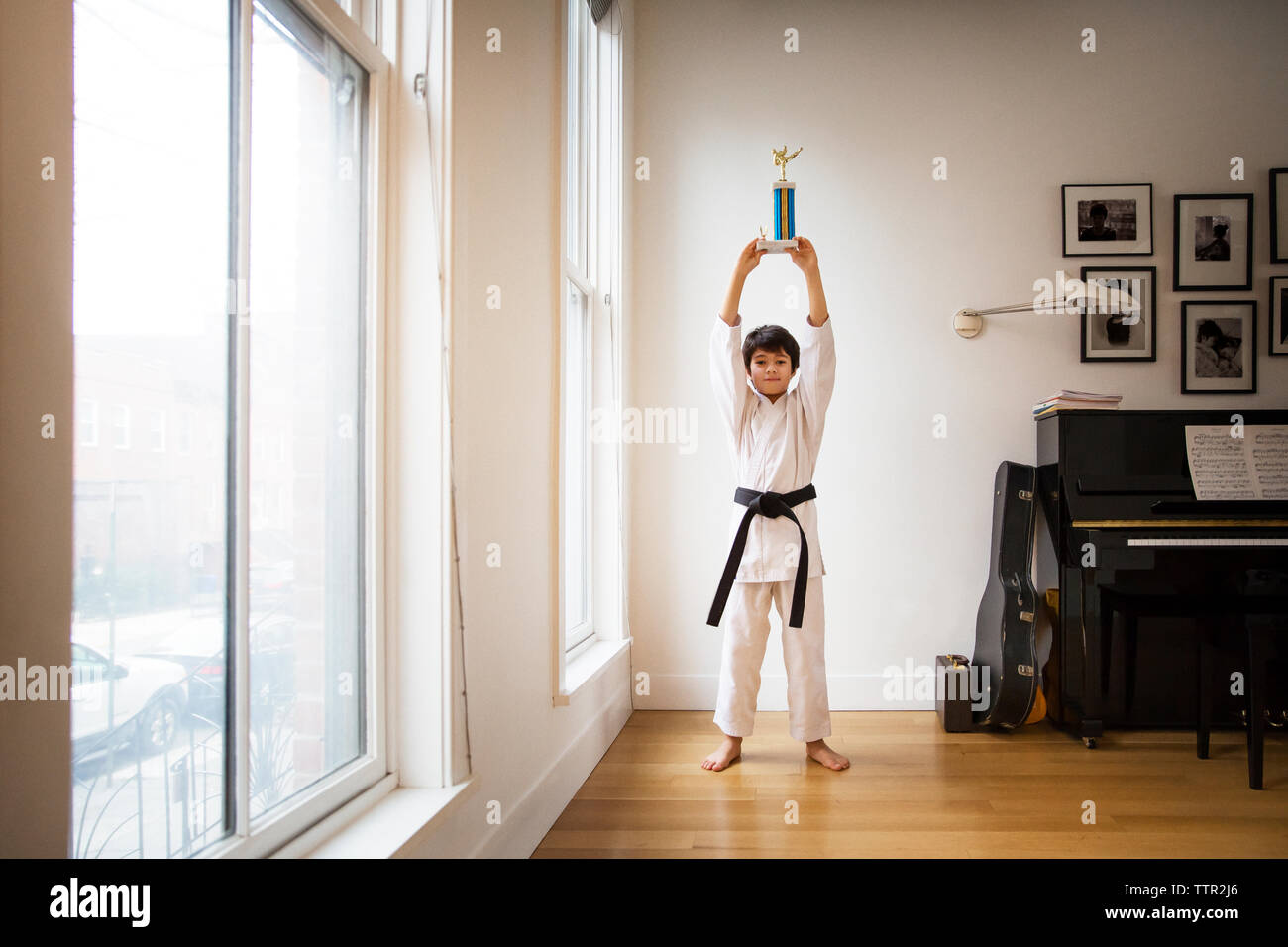Ragazzo holding award e in piedi dalla finestra a casa Foto Stock