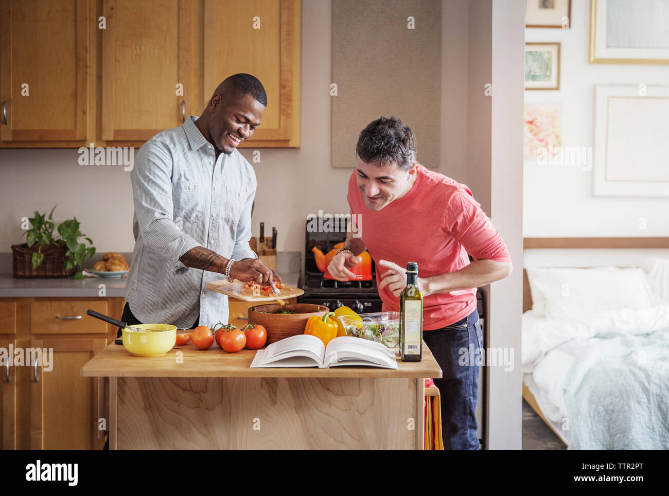 Felice multi-etnico coppia gay preparare il cibo in cucina a casa Foto Stock