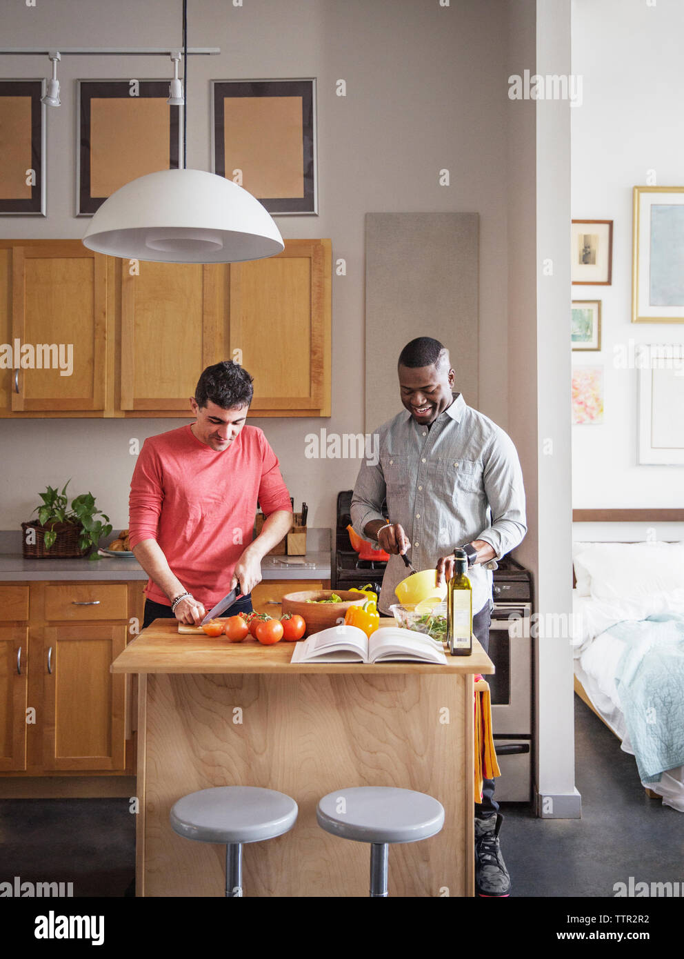 Multi-etnico coppia gay preparare il cibo in cucina a casa Foto Stock