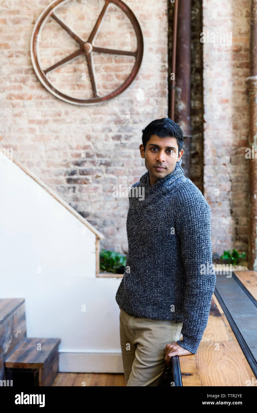 Ritratto di fiducioso adulto medio imprenditore appoggiata sul tavolo in ufficio creativo Foto Stock