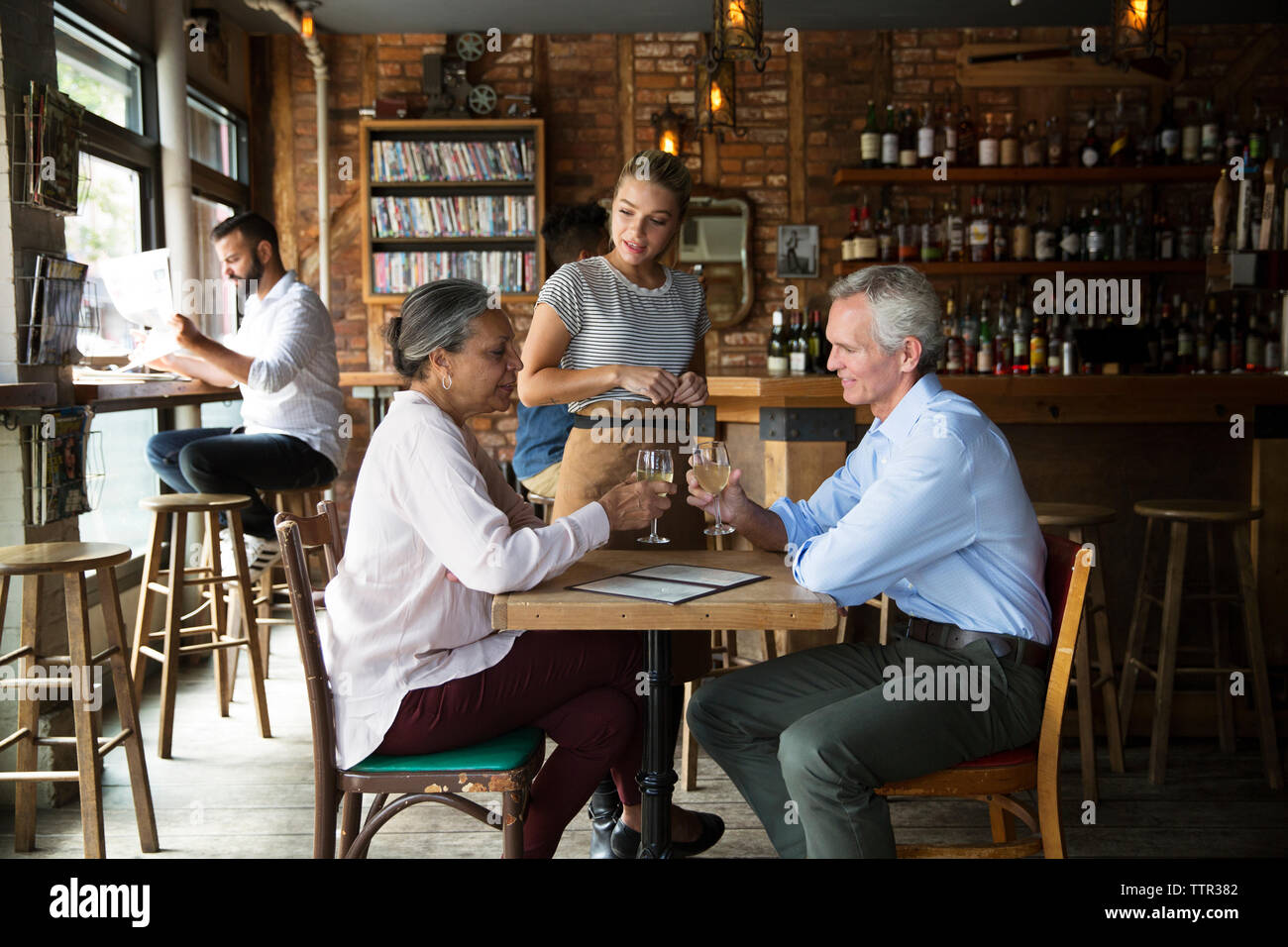 Cameriera di parlare ai clienti seduti al cafe Foto Stock