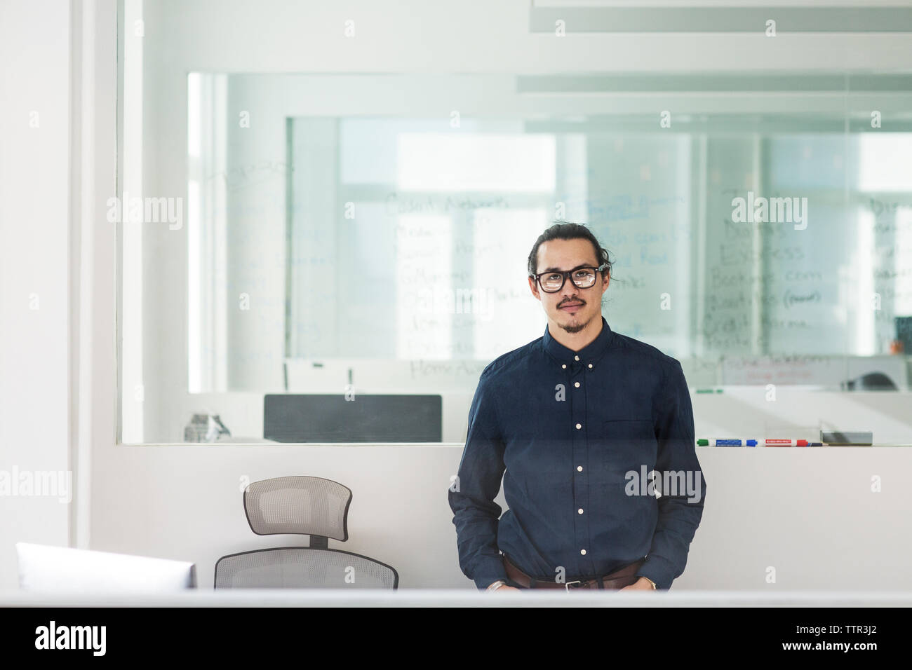 Ritratto di imprenditore in piedi in ufficio visto attraverso la finestra Foto Stock