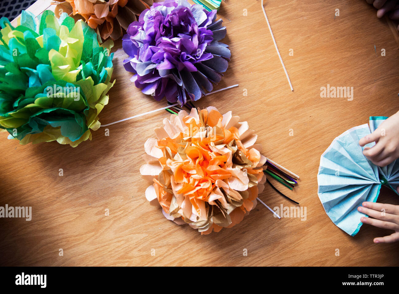 Immagine ritagliata della ragazza facendo fiori di carta a tavola Foto Stock