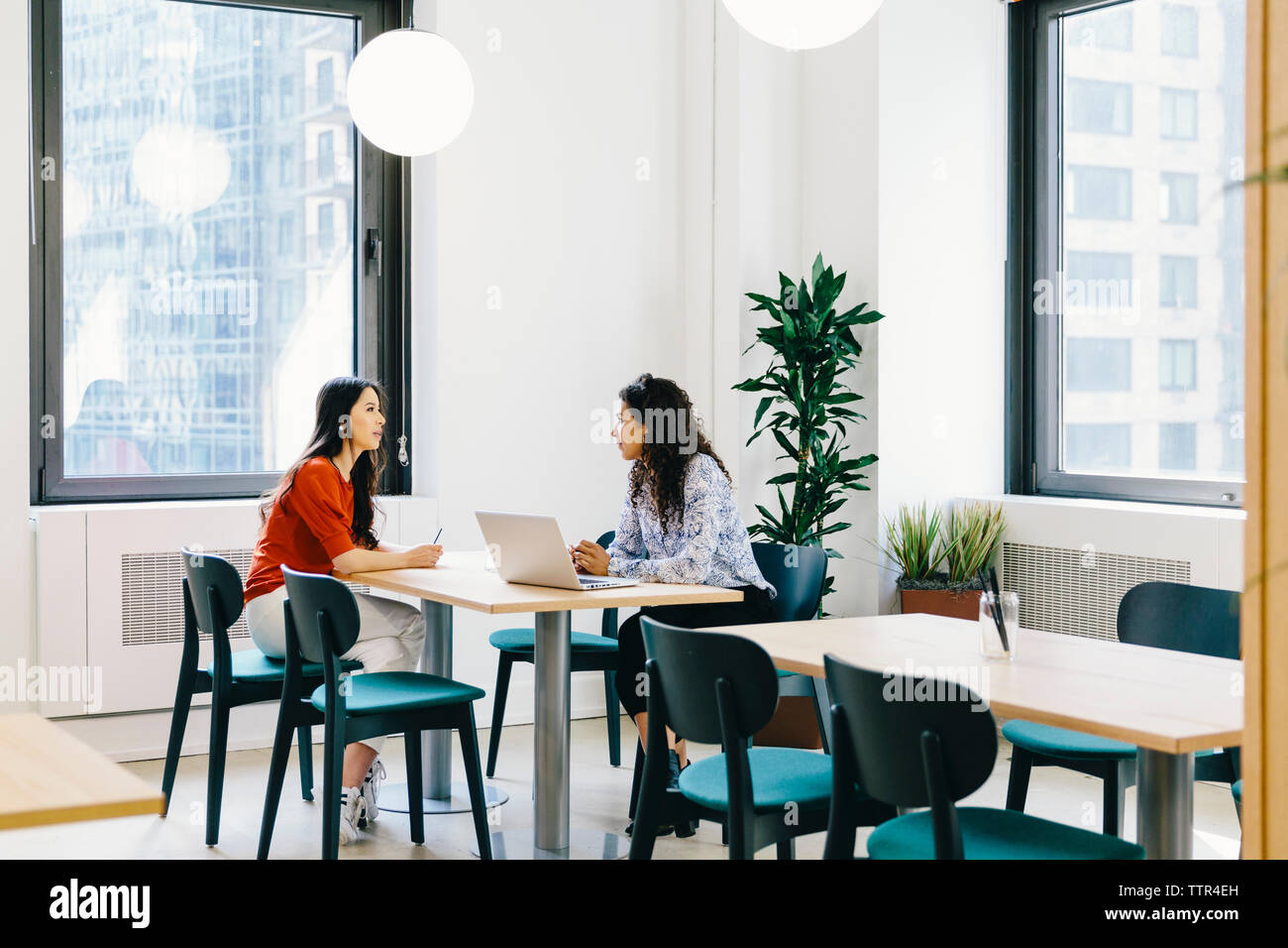 Femmina brainstorming colleghi seduti su sedie a scrivania in ufficio Foto Stock