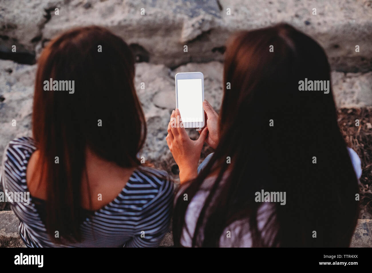 Angolo di alta vista di amici di sesso femminile utilizzando smart phone all'aperto Foto Stock