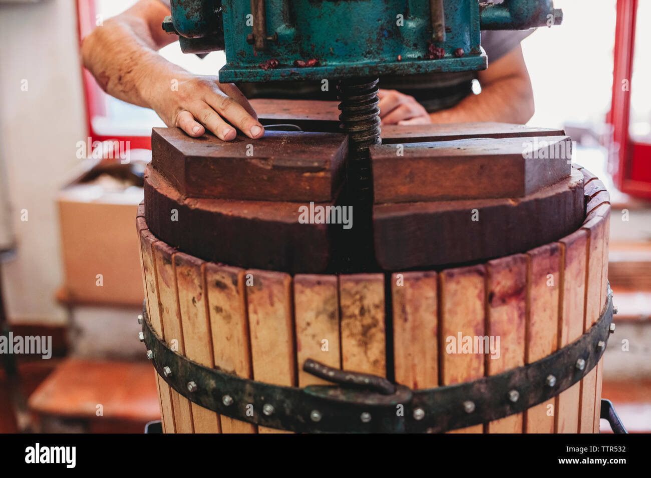 Mani tagliate dei maschi di vignaiolo utilizzando attrezzature industriali mentre fare il vino in botte in fabbrica Foto Stock