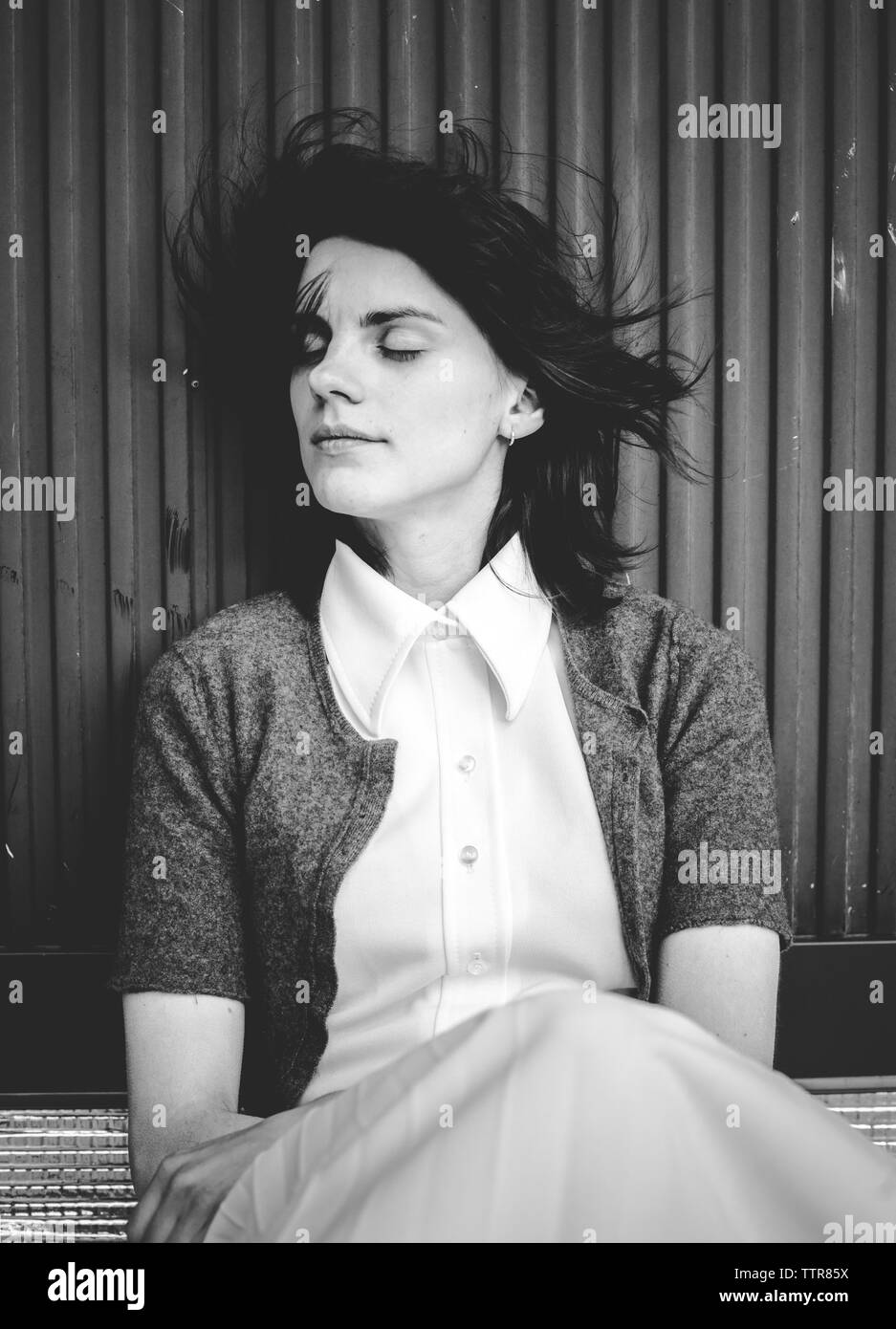 Close-up di donna con gli occhi chiusi seduta dalla parete Foto Stock