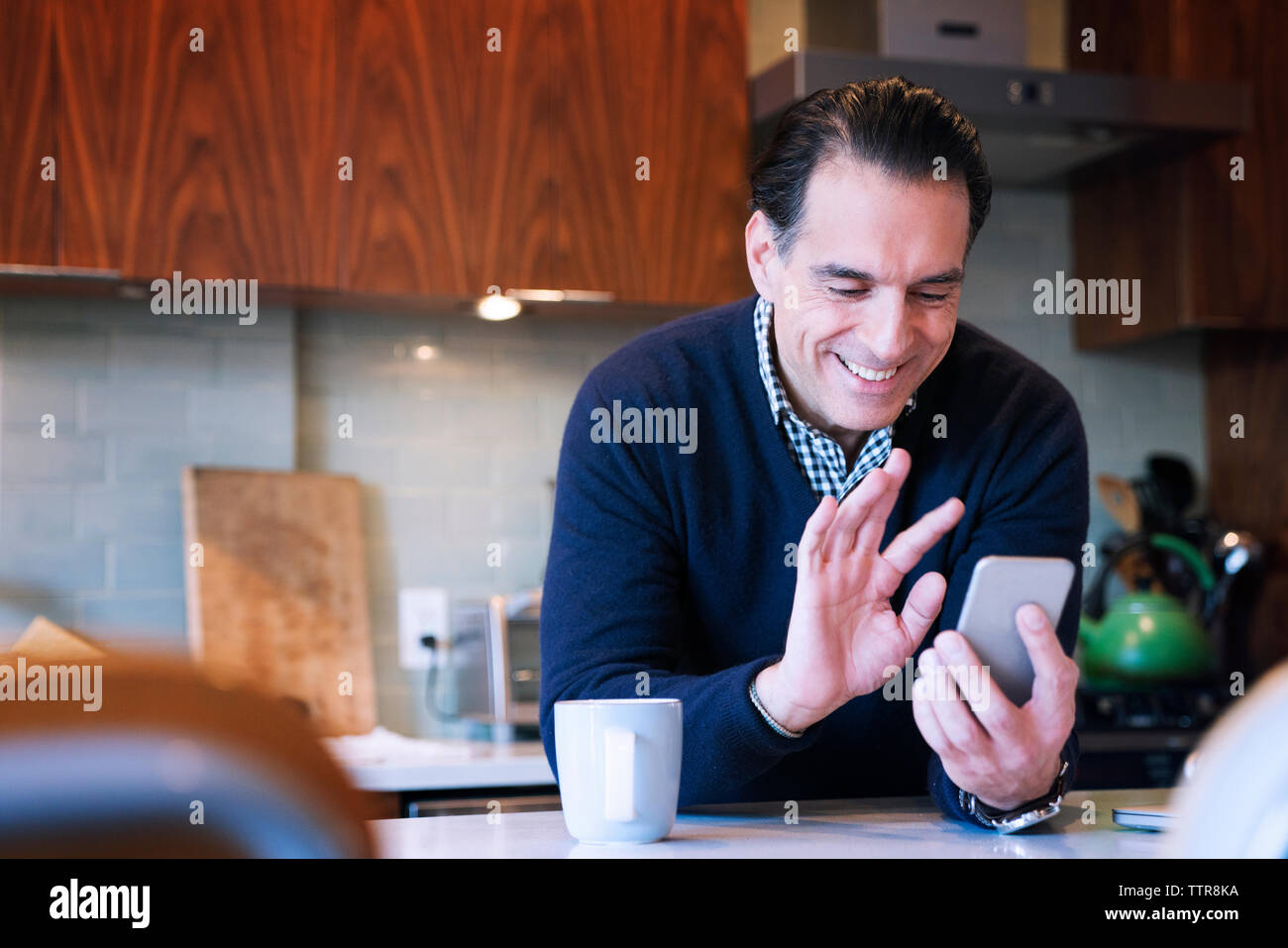 L'uomo sventolare mentre guardando smart phone in home Foto Stock