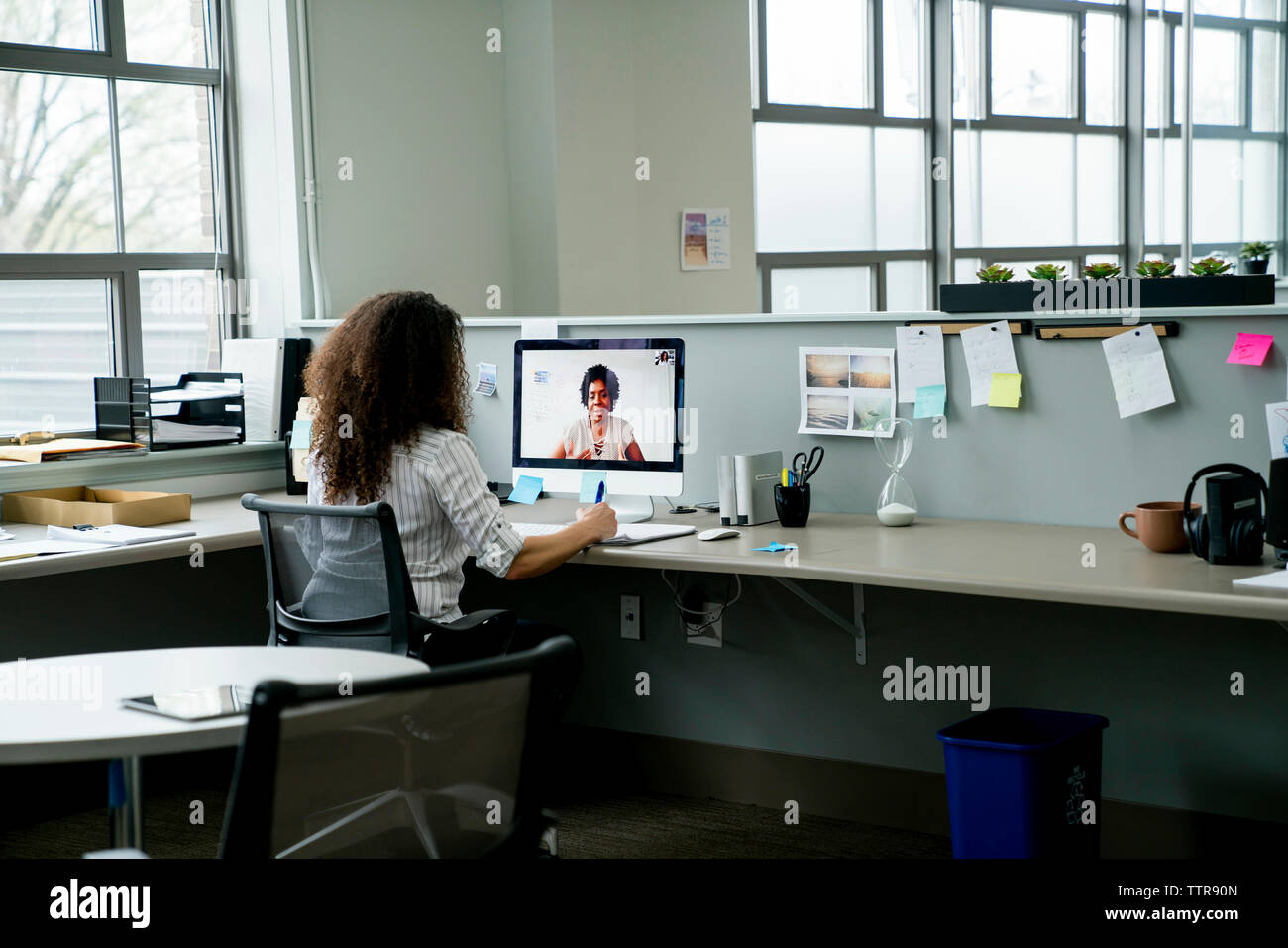 Vista posteriore di imprenditrice discutendo con la collega tramite video conferenza in Office Foto Stock