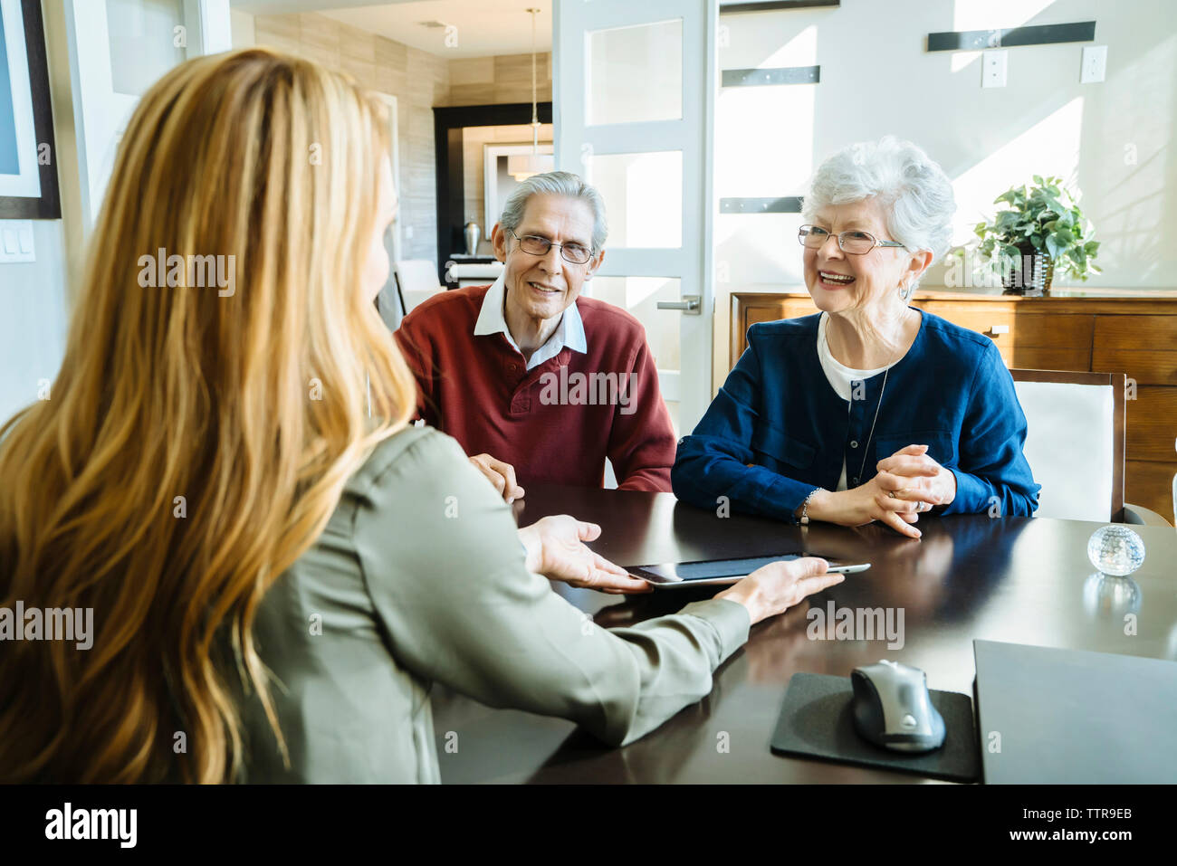 Femmina consulente finanziario spiegando piano per coppia senior sul Tablet PC in ufficio Foto Stock