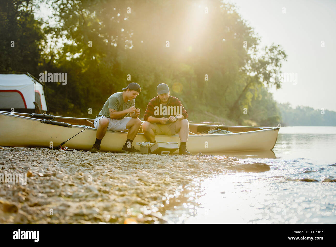 Amici maschio regolare la pesca affronta mentre è seduto sulla barca al campeggio Foto Stock