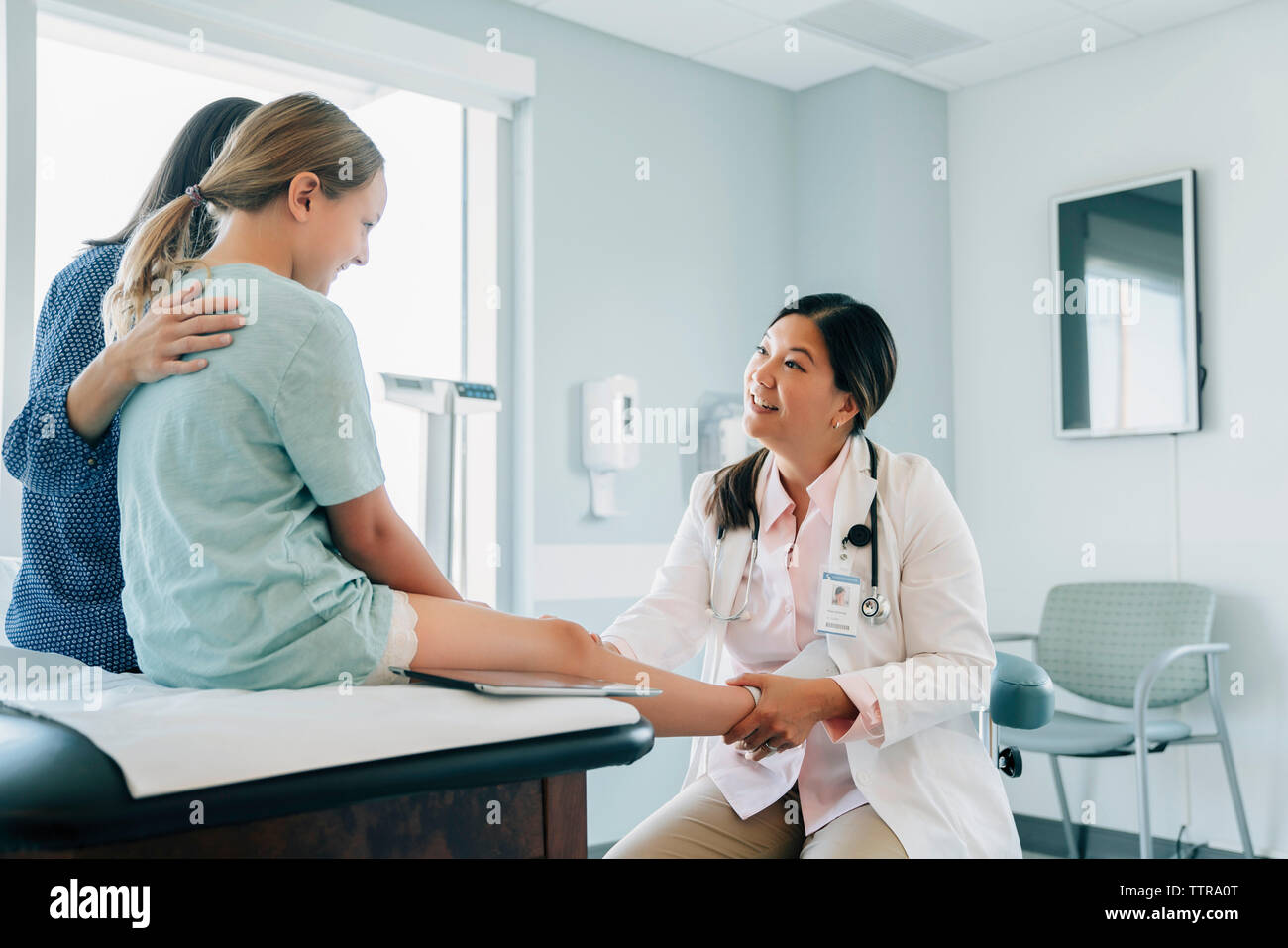 Pediatra esaminando la ragazza del ginocchio in medical sala esame Foto Stock