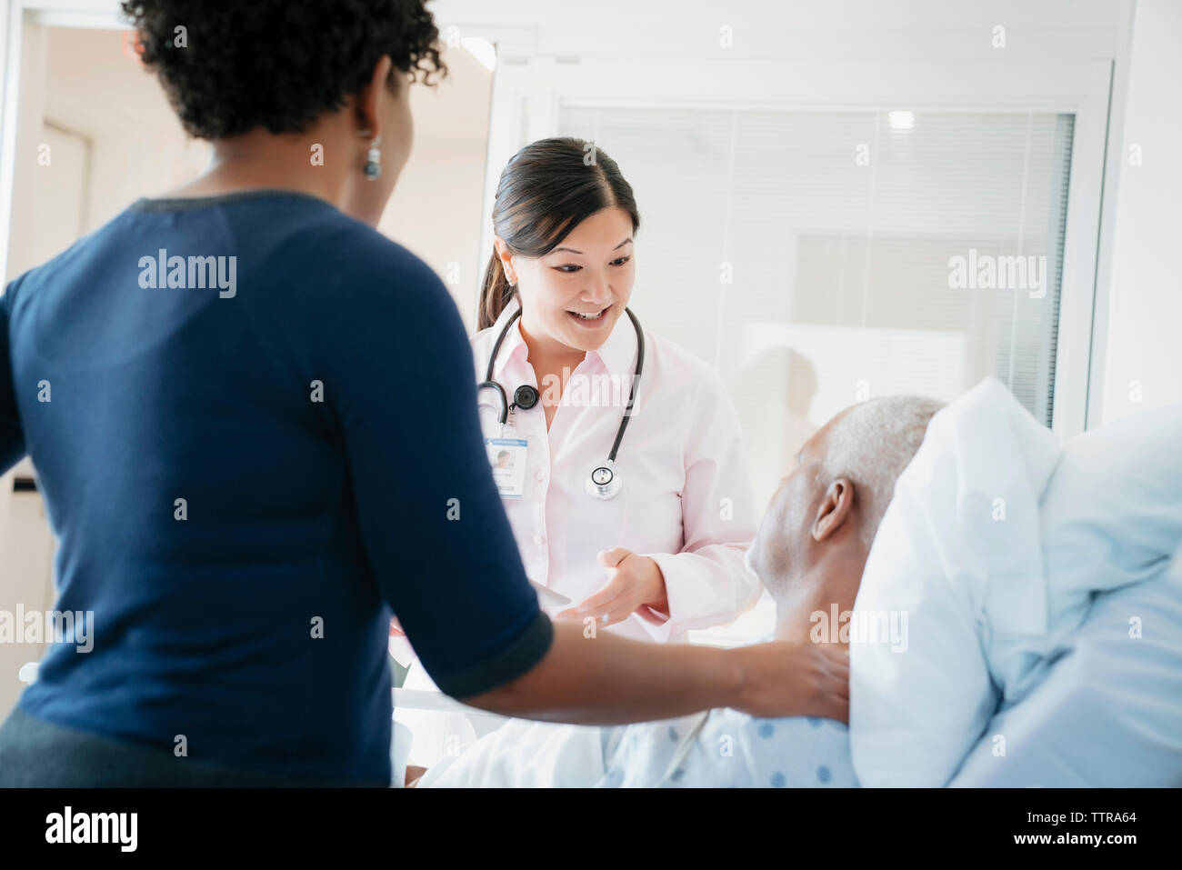 Medico donna parlando con i senior paziente sdraiato dalla figlia in ospedale Foto Stock