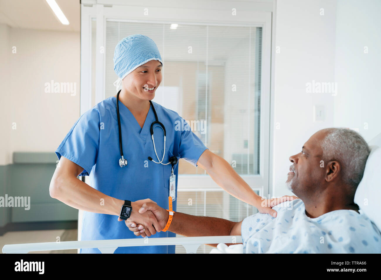 Fiducioso chirurgo stringono le mani con i senior paziente in ospedale Foto Stock