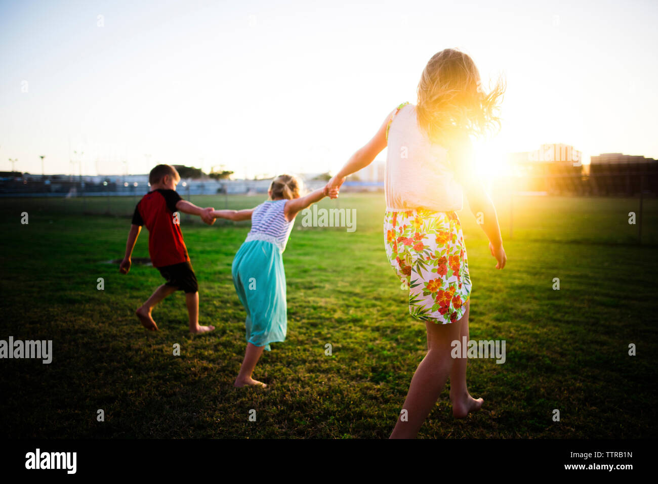 Madre e bambini che giocano al parco durante il tramonto Foto Stock