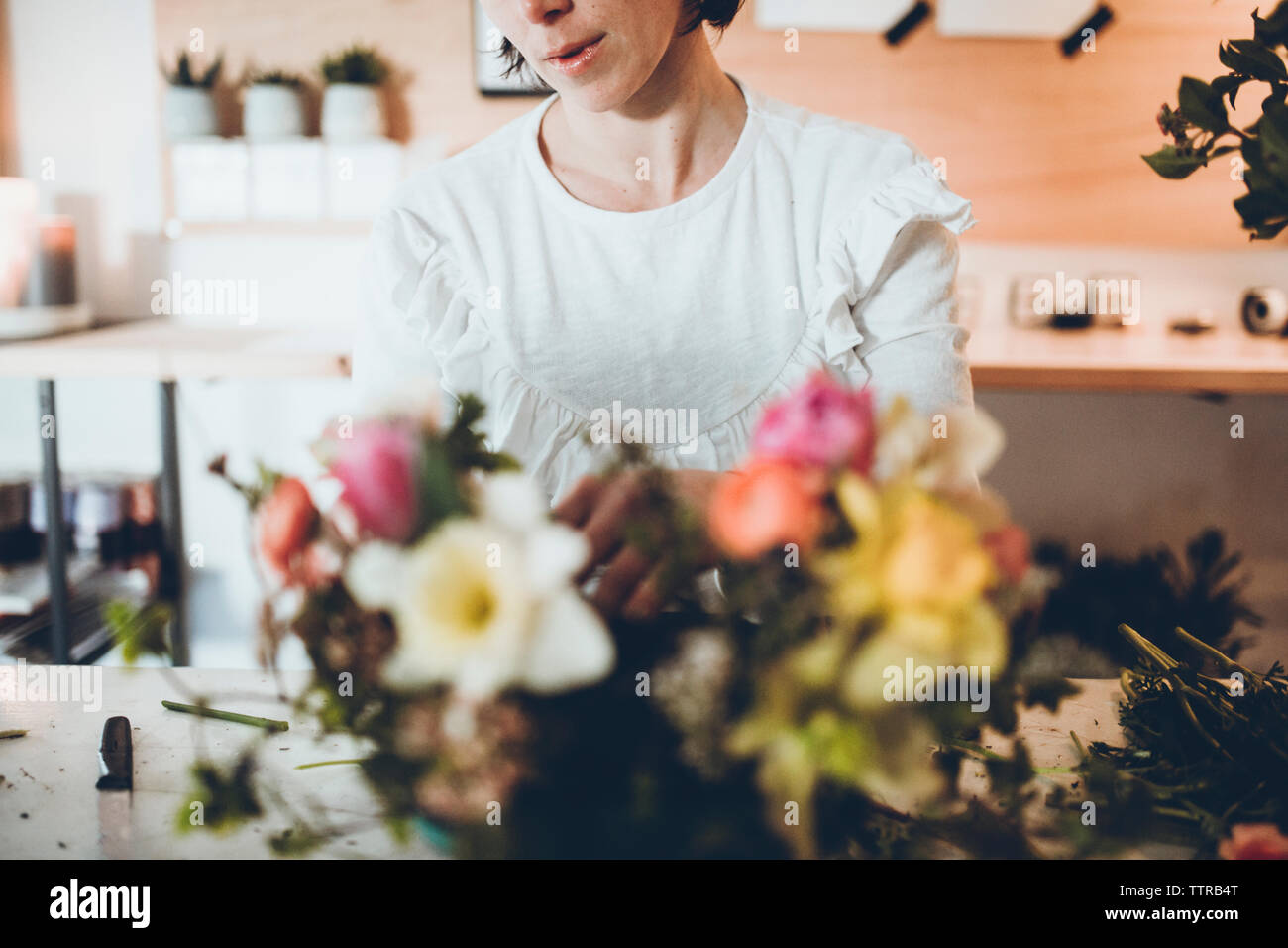 Sezione mediana di un fioraio disponendo dei fiori in negozio Foto Stock
