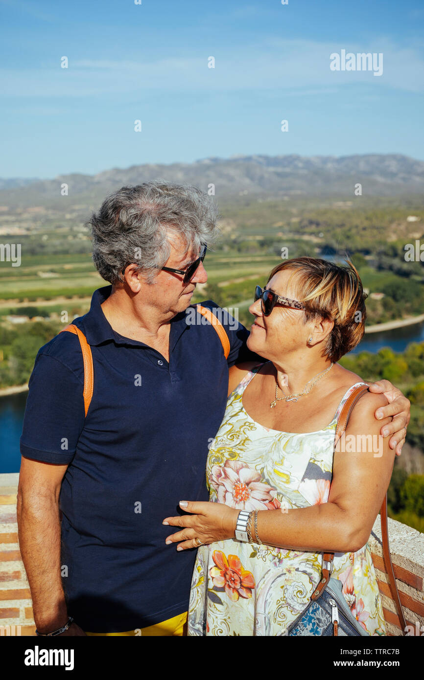 Romantico coppia senior indossando occhiali da sole mentre permanente al punto di osservazione contro il cielo durante la giornata di sole Foto Stock