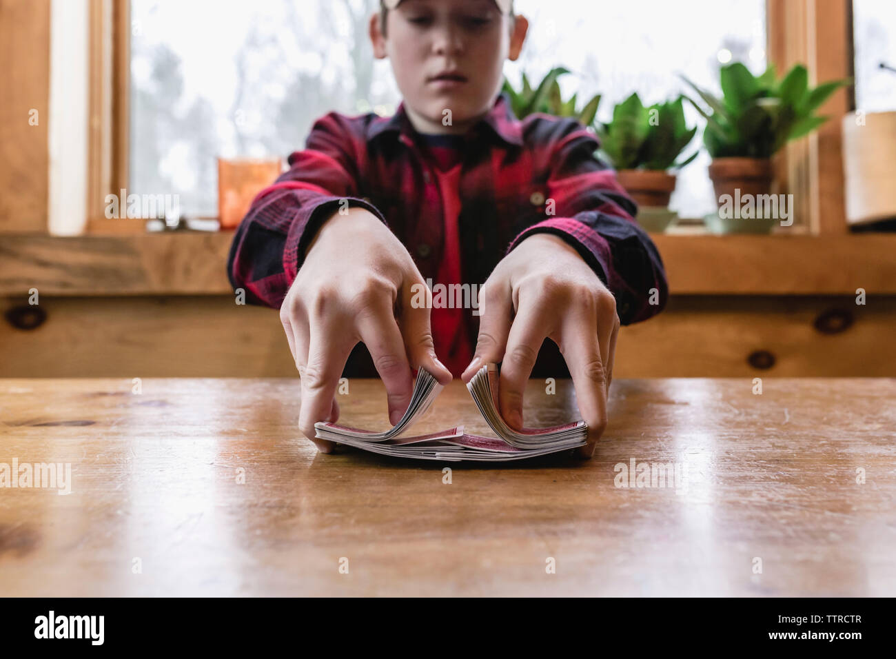 Ragazzo adolescente rimescolare le carte sul tavolo di legno a cottage Foto Stock