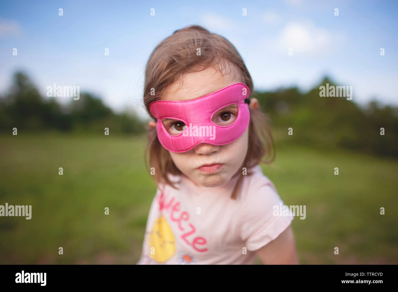 Close-up verticale di una ragazza che indossa la maschera mentre in piedi contro il cielo a park Foto Stock