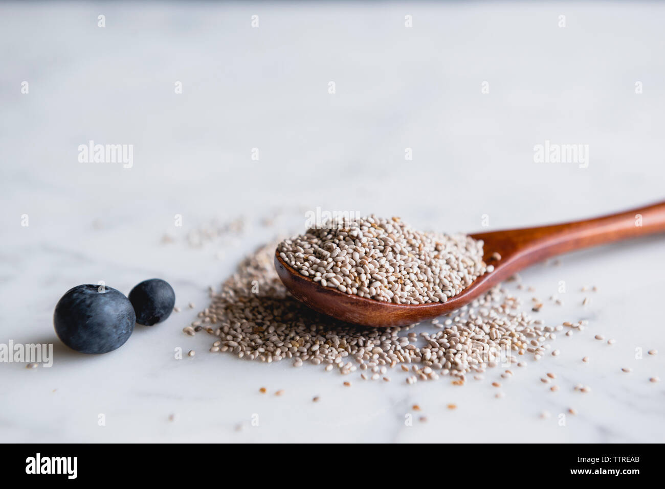 Il cucchiaio di legno con semi di Chia e mirtilli sul bancone di marmo Foto Stock