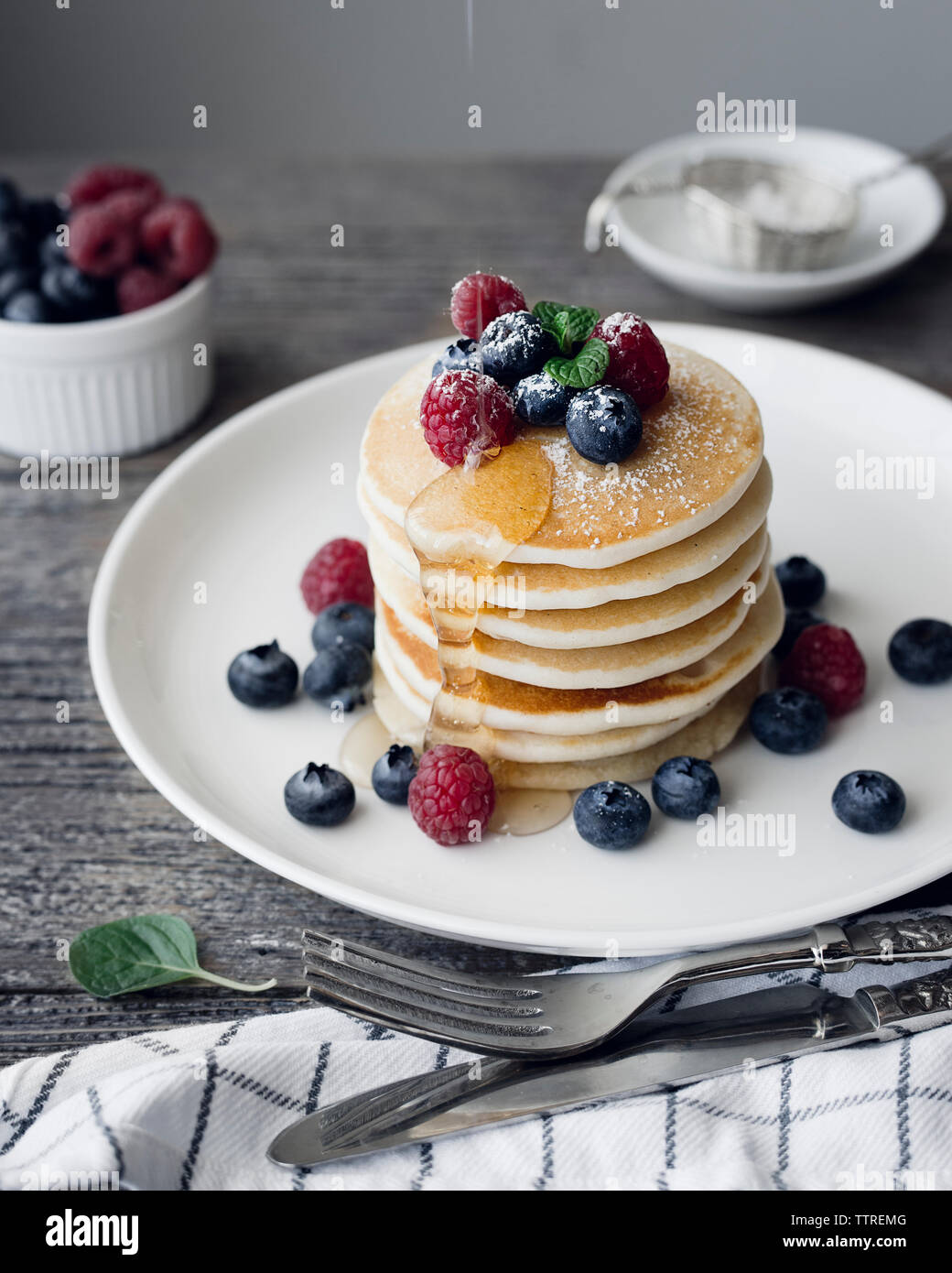 Pancake con fragole fresche e mirtilli in blu piastra in ceramica, e fluente  dal miele Il miele in legno bilanciere, servita con Foto stock - Alamy