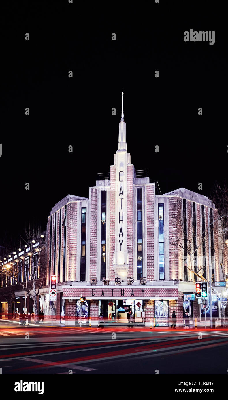 Percorsi di luce per la circolazione su strada illuminata da Cathay theatre contro il cielo di notte Foto Stock