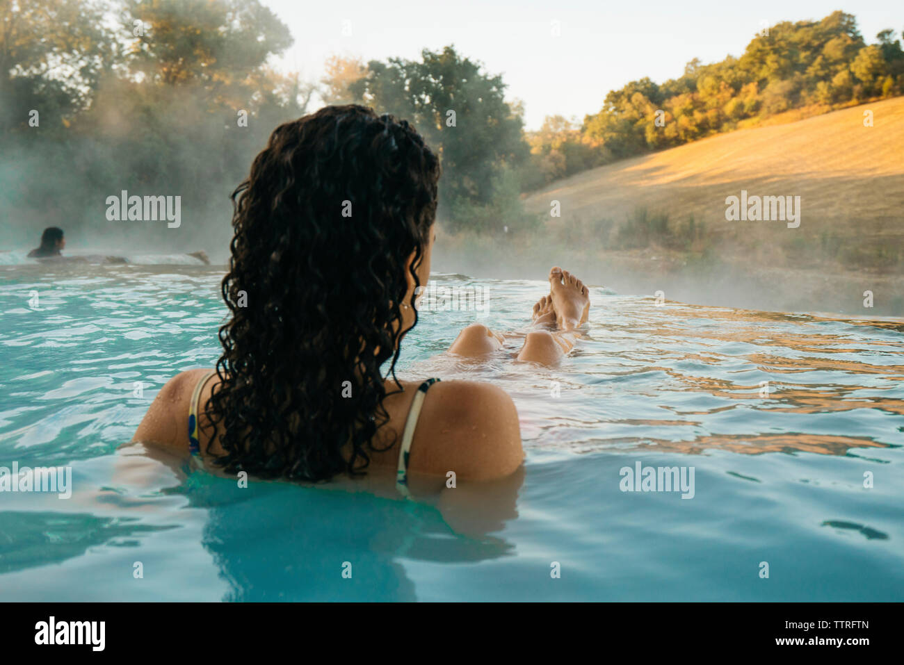 Vista posteriore della donna rilassante in piscina termale Foto Stock