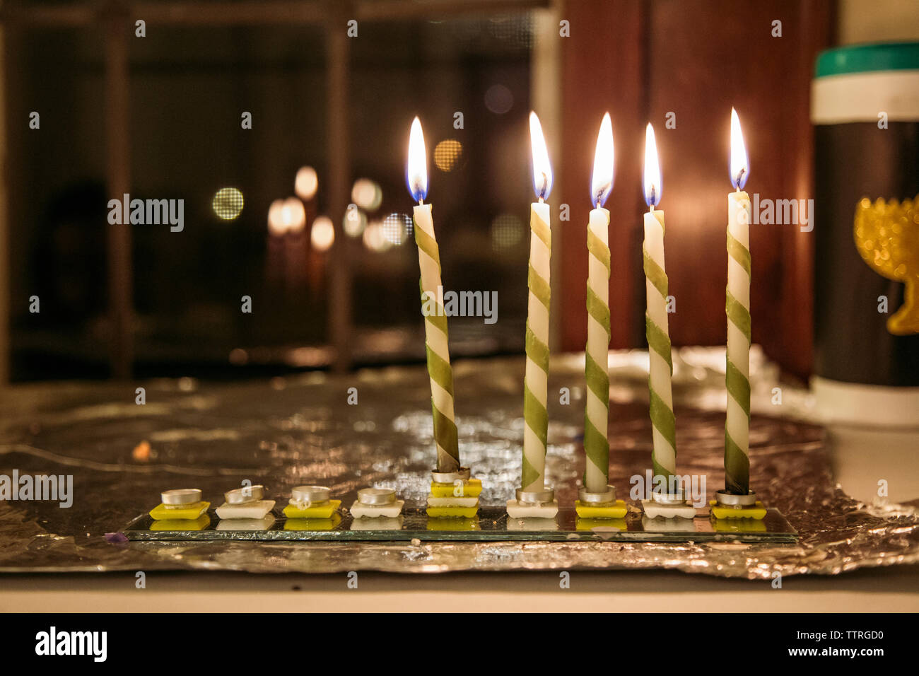 Close-up di candele illuminate su vetro a tavola durante Chanukah Foto Stock