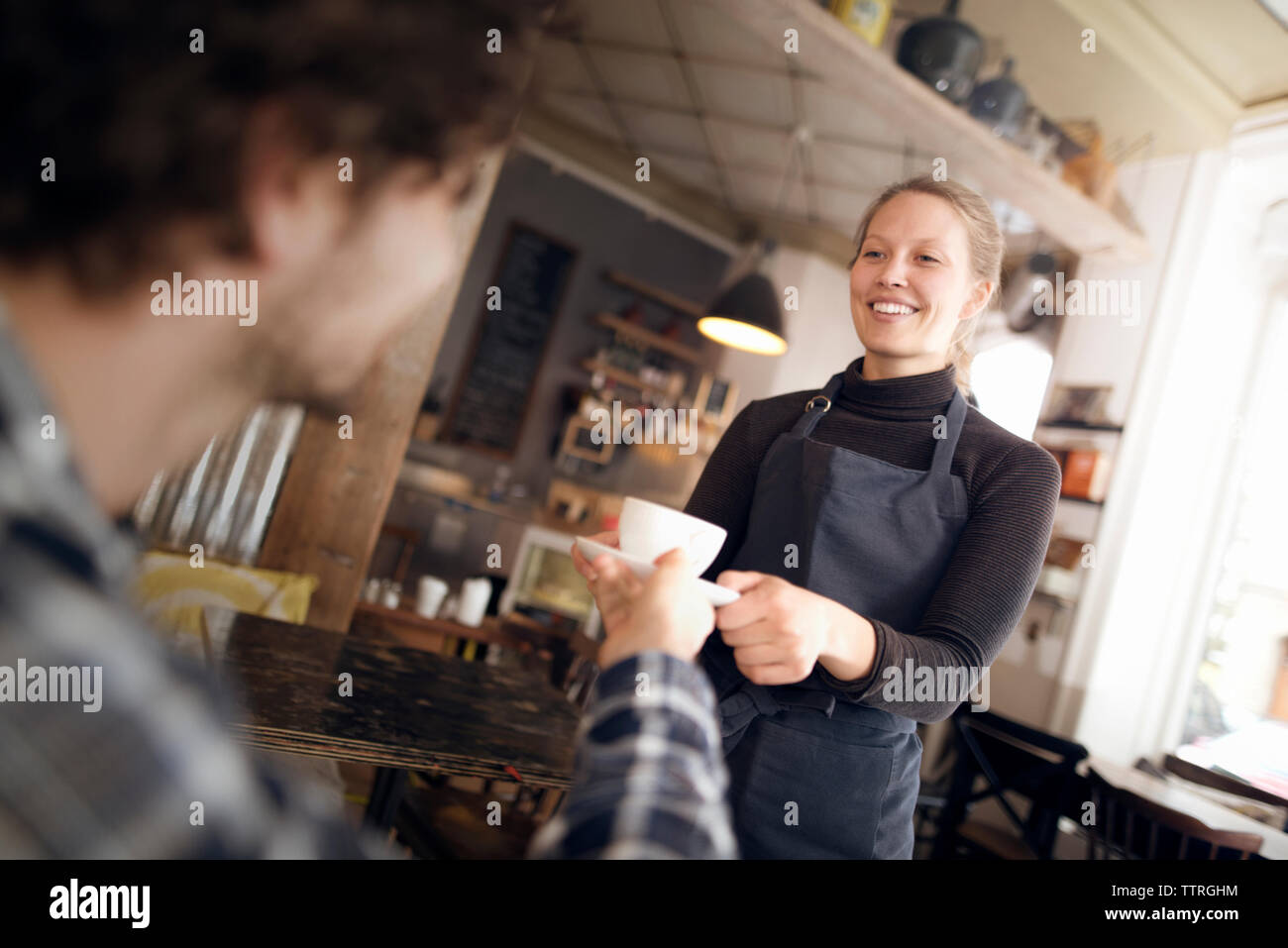 Felice cameriera che serve caffè all uomo in cafe Foto Stock