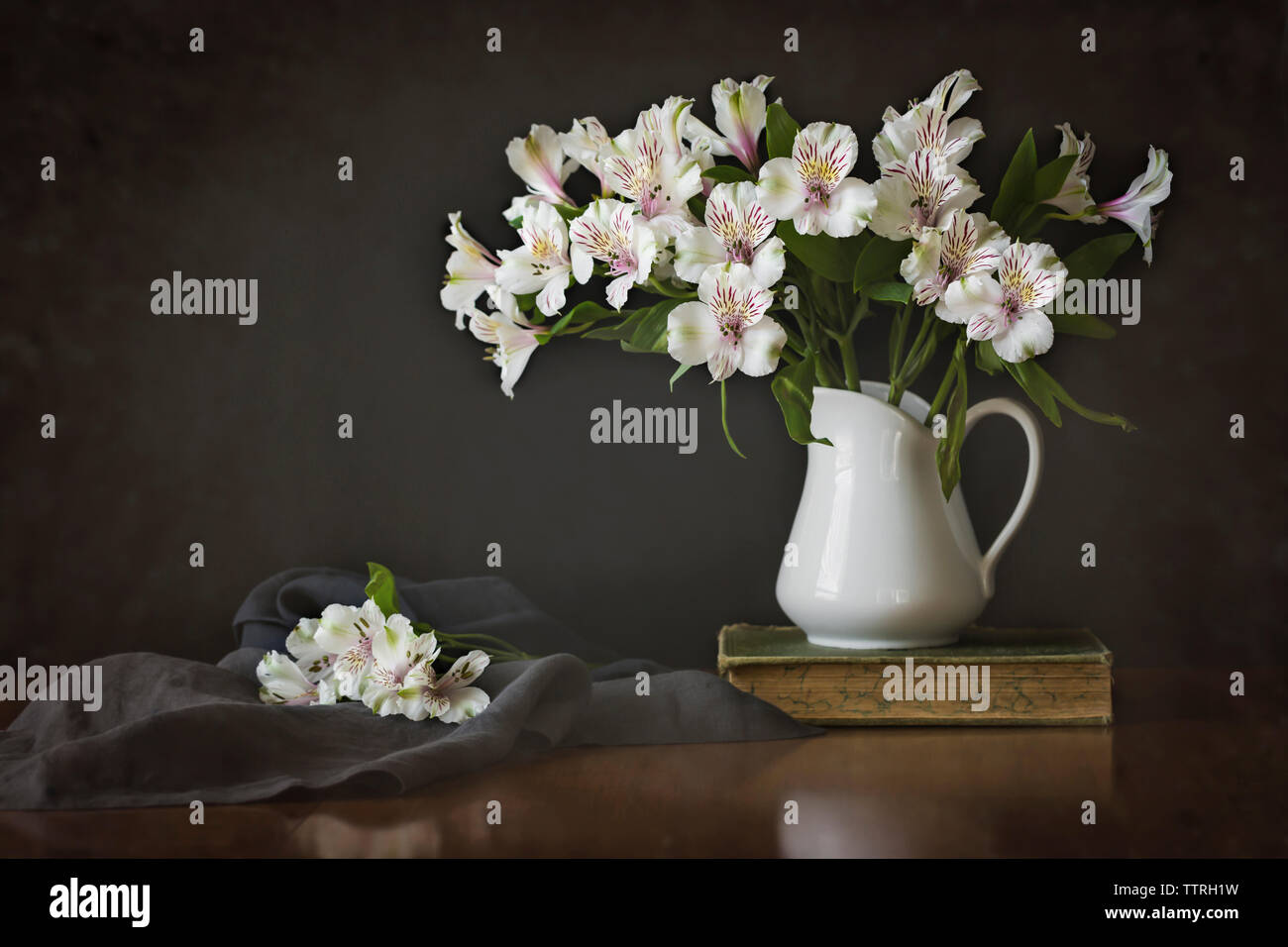 Gigli peruviana in vaso con libro e tessuto sul tavolo di legno Foto Stock