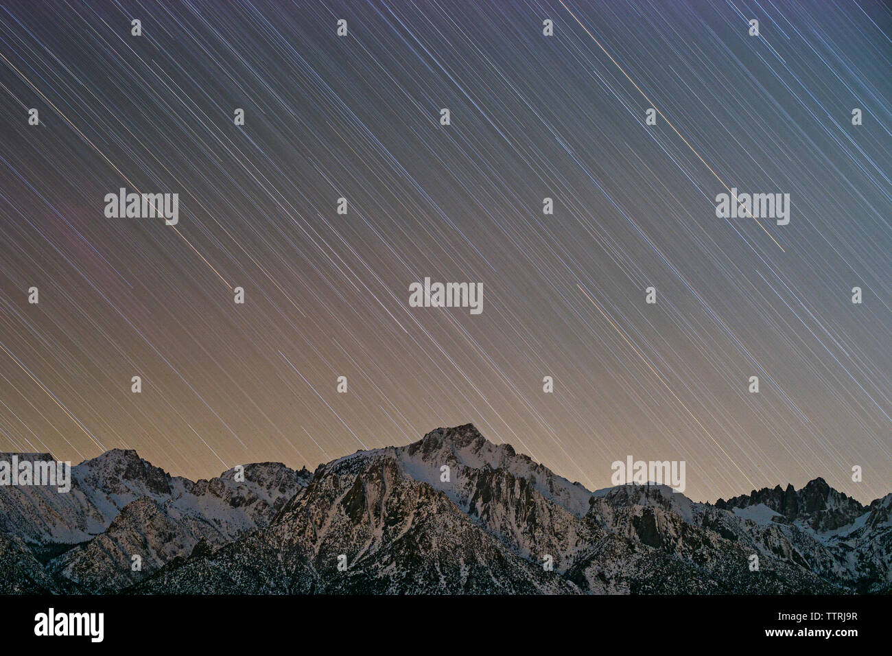 Basso angolo di vista Tracce stellari oltre nevato mountain durante la notte Foto Stock