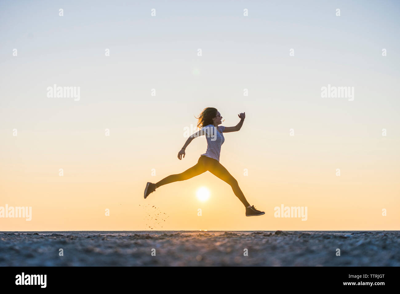 Il livello superficiale della donna che si tuffa in spiaggia contro il cielo chiaro durante il tramonto Foto Stock