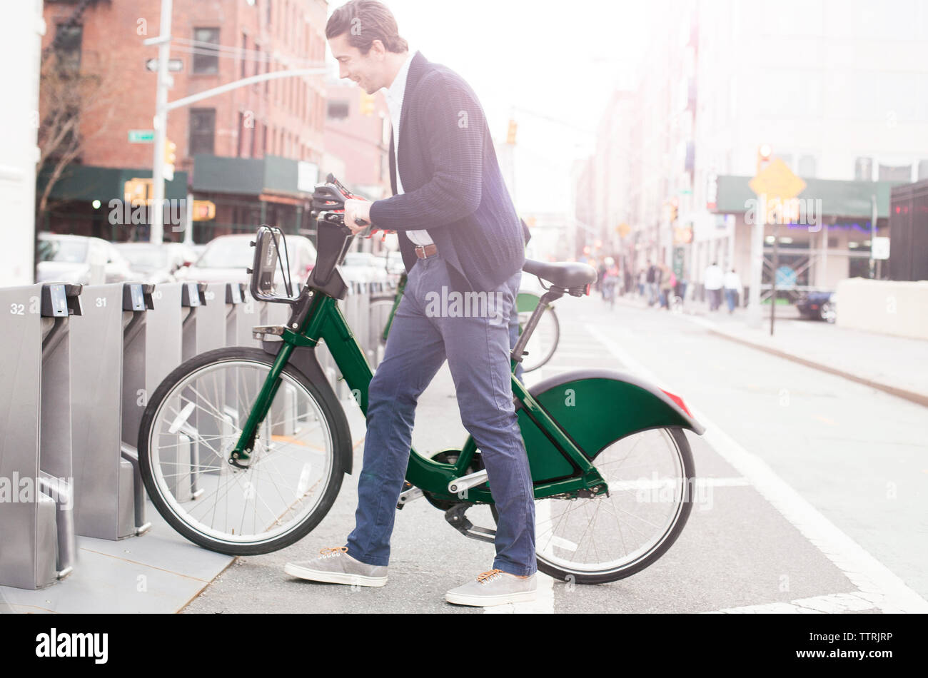 Vista laterale di uomo felice di bloccaggio quota di bici su strada Foto Stock