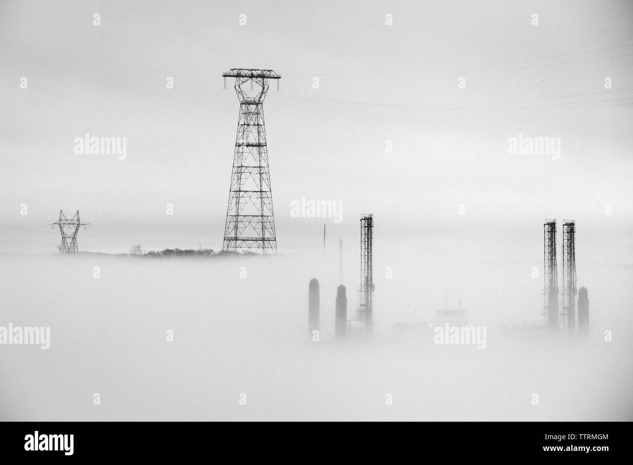 Pilone dell contro il cielo durante la nebbia meteo Foto Stock