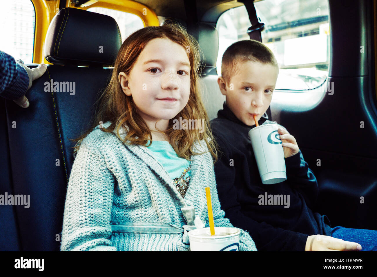Ritratto di fratelli con drink seduto in auto Foto Stock