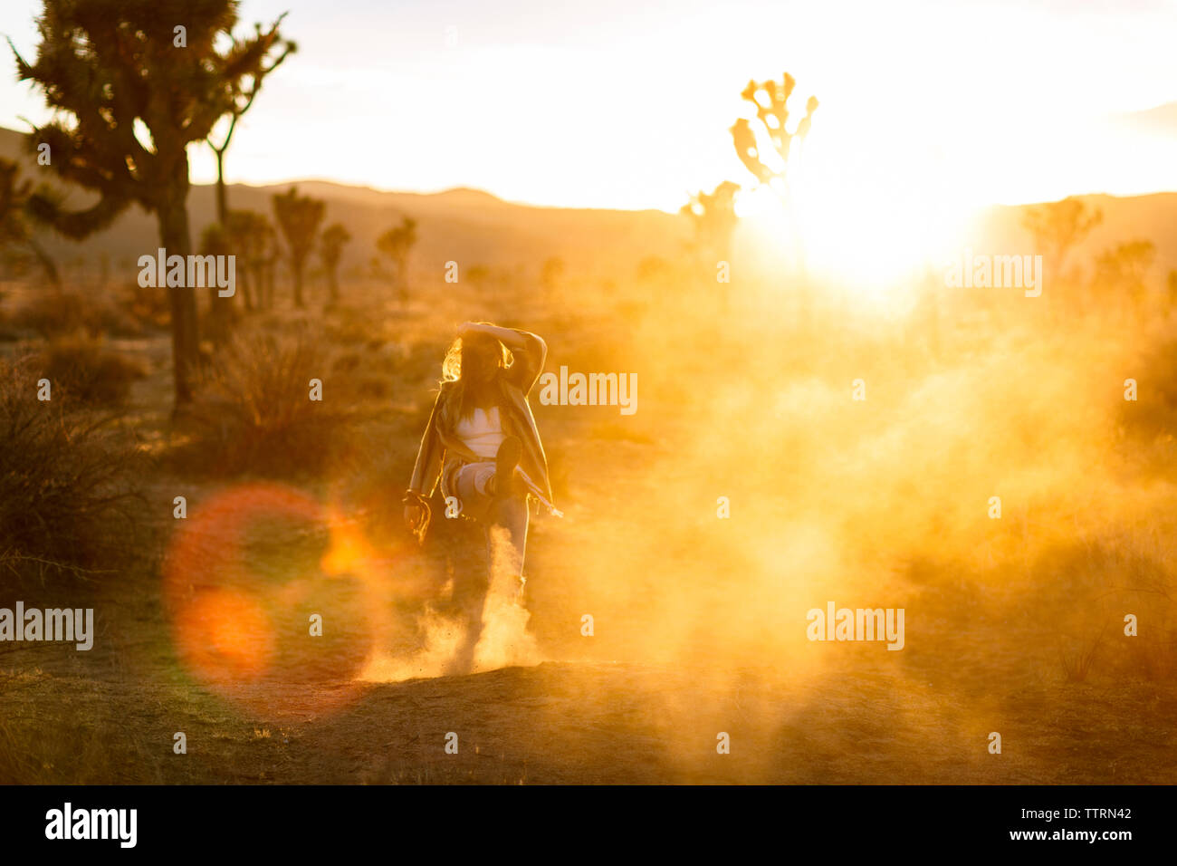 Lunghezza completa di giocosa donna calci sabbia sul campo a Joshua Tree National Park Foto Stock