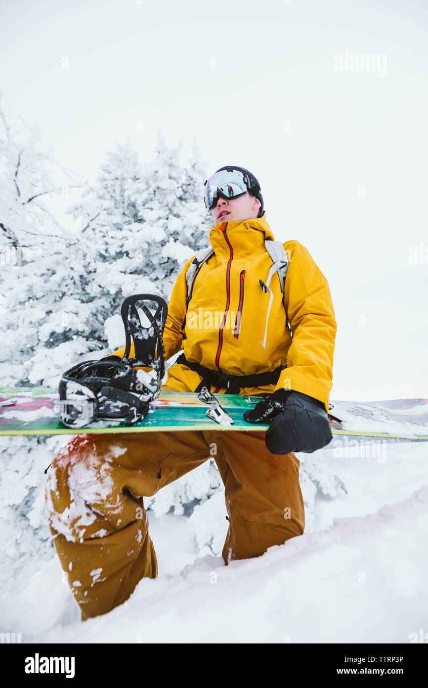 Giovani snowboarder è pronta per lo snowboard in un giallo brillante camicia Foto Stock