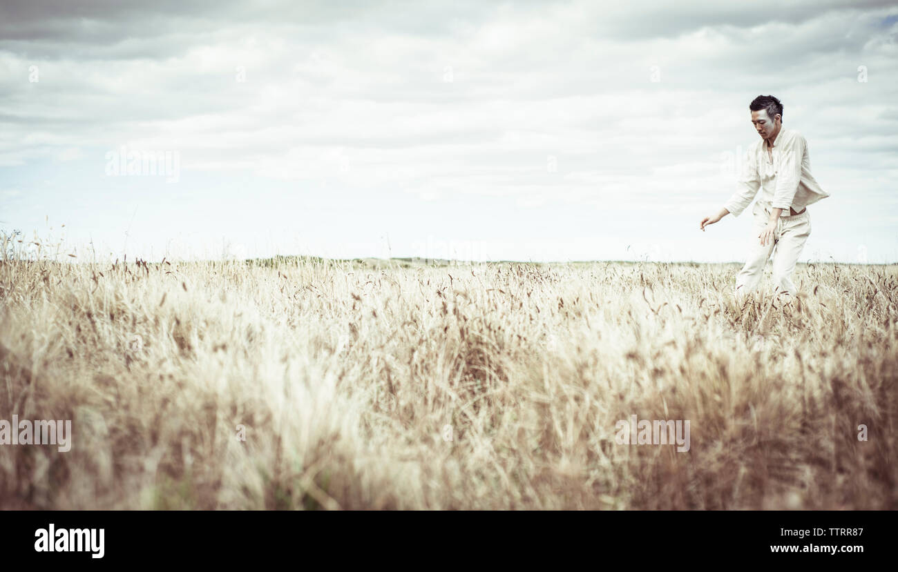 Uomo che danzano sul campo contro il cielo nuvoloso presso l'azienda Foto Stock