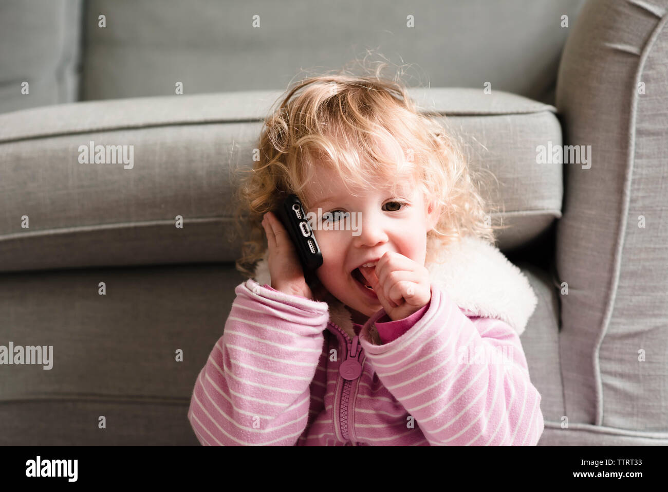 Ragazza parlando al telefono cellulare dalla poltrona di casa Foto Stock