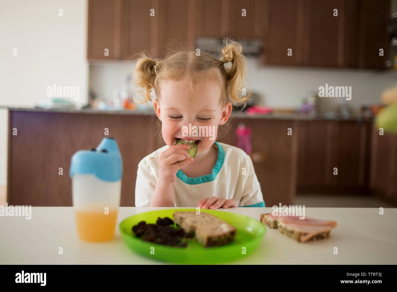 Ragazza avente il cibo durante la seduta a tavola Foto Stock