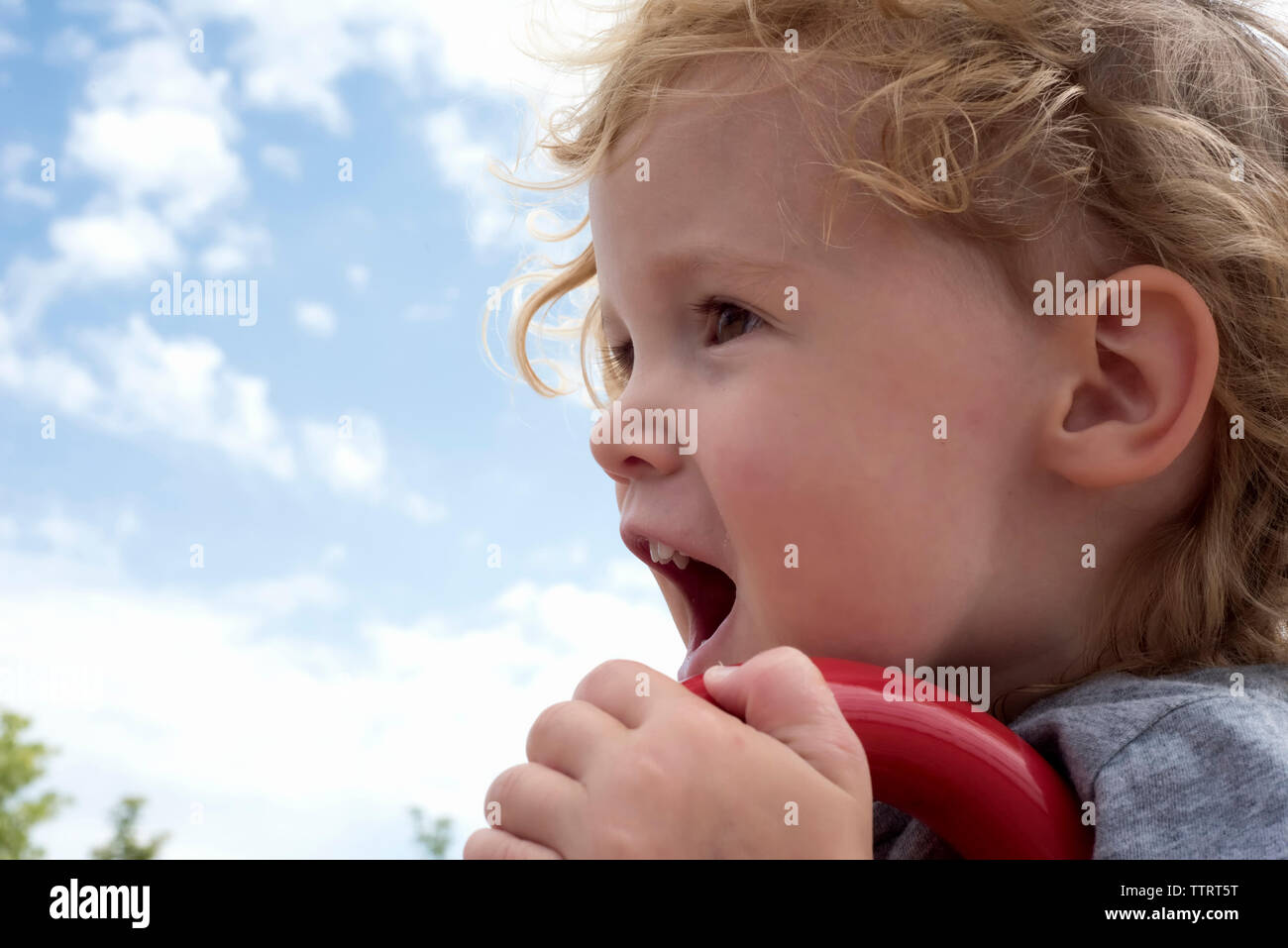 Close-up di carino ragazza grida al parco giochi contro sky Foto Stock