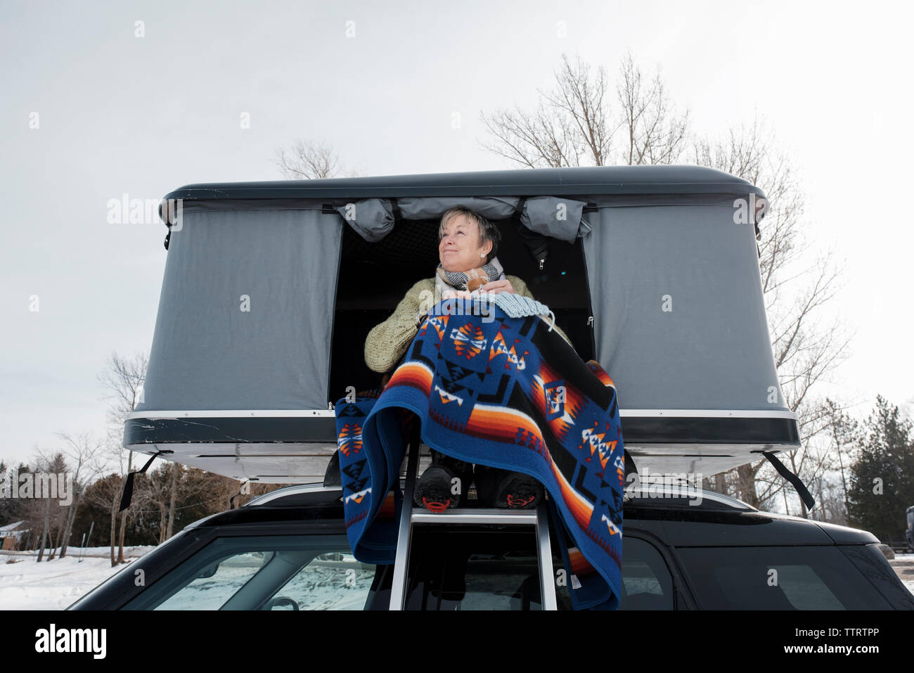 Maglieria donna mentre è seduto nella tenda del tetto sulla vettura durante il periodo invernale Foto Stock