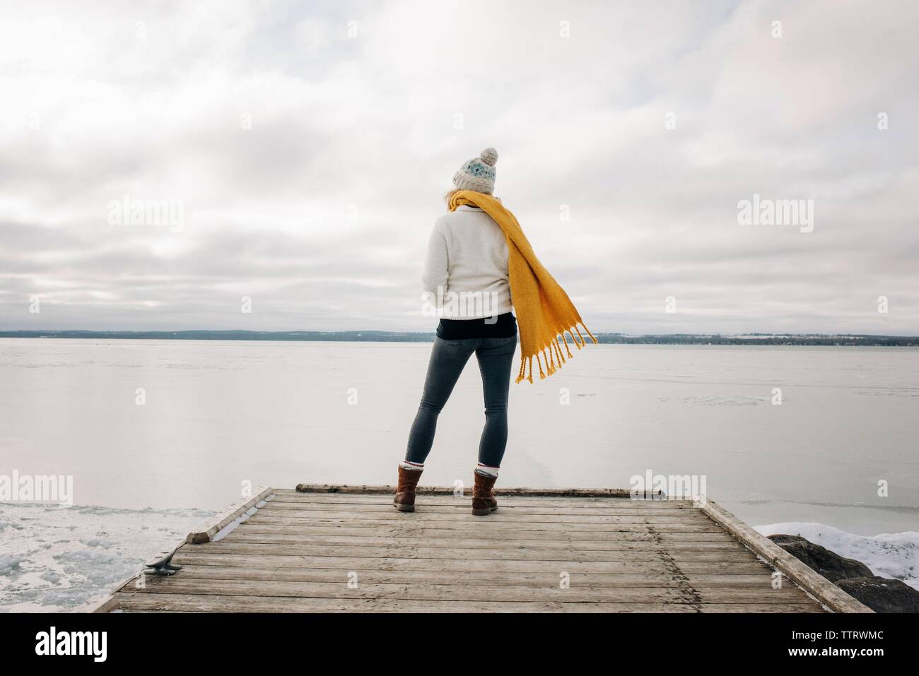 Donna in piedi sull'estremità di un molo jetty guardando fuori per l'acqua Foto Stock
