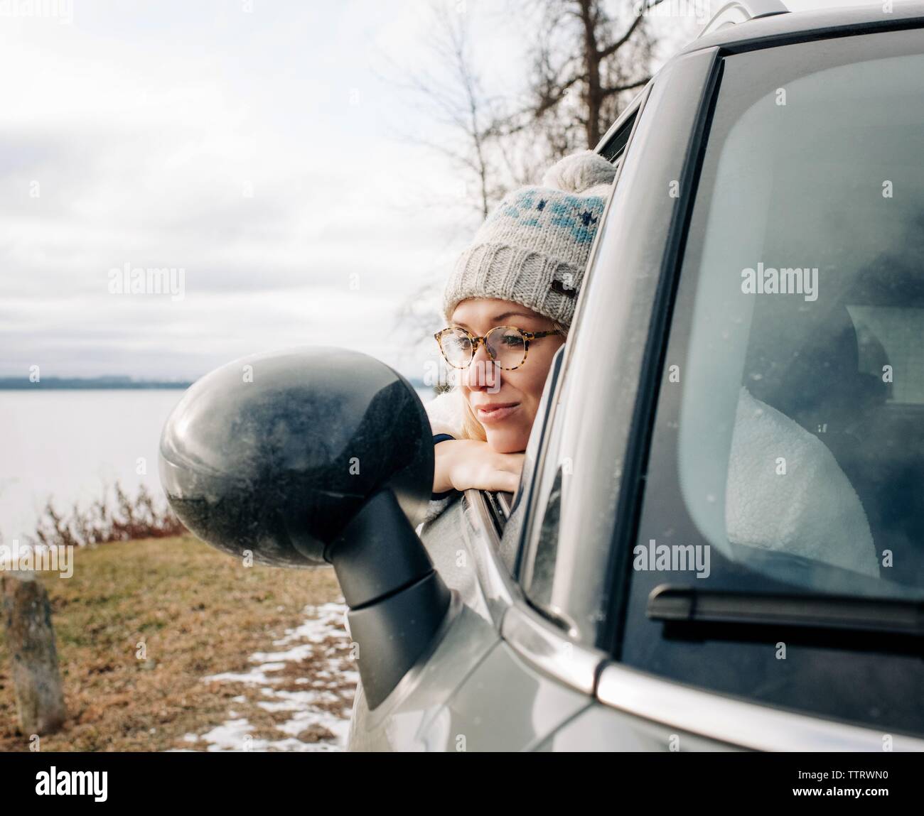 Ritratto di donna bionda con gli occhiali guardando fuori della finestra auto acqua Foto Stock