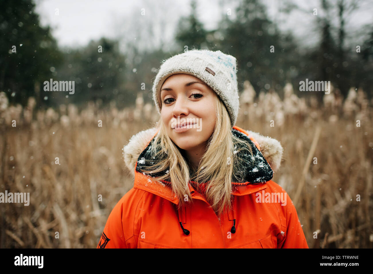 Donna sorridente nella neve in inverno con cappello e il cappotto Foto Stock