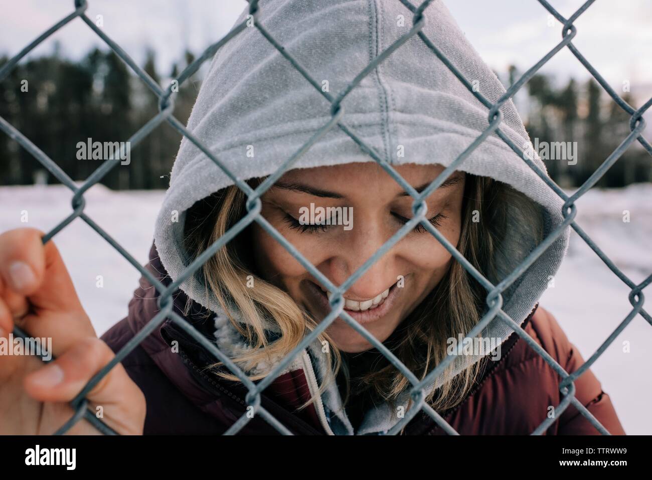 Ritratto di donna sorridente tenuta su di una recinzione metallica con cappa su Foto Stock
