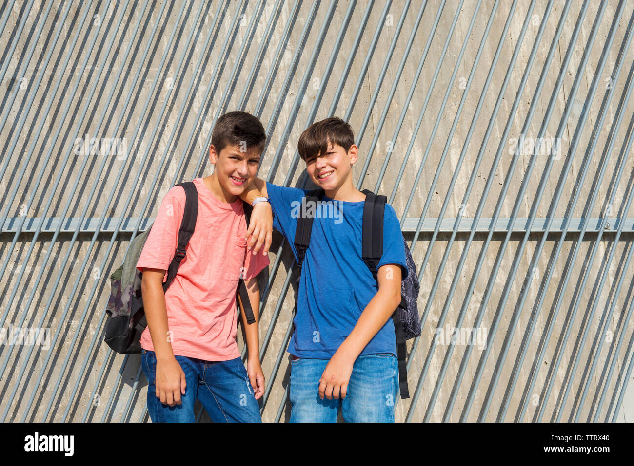 Ritratto di felice amici in piedi dalla parete durante la giornata di sole Foto Stock