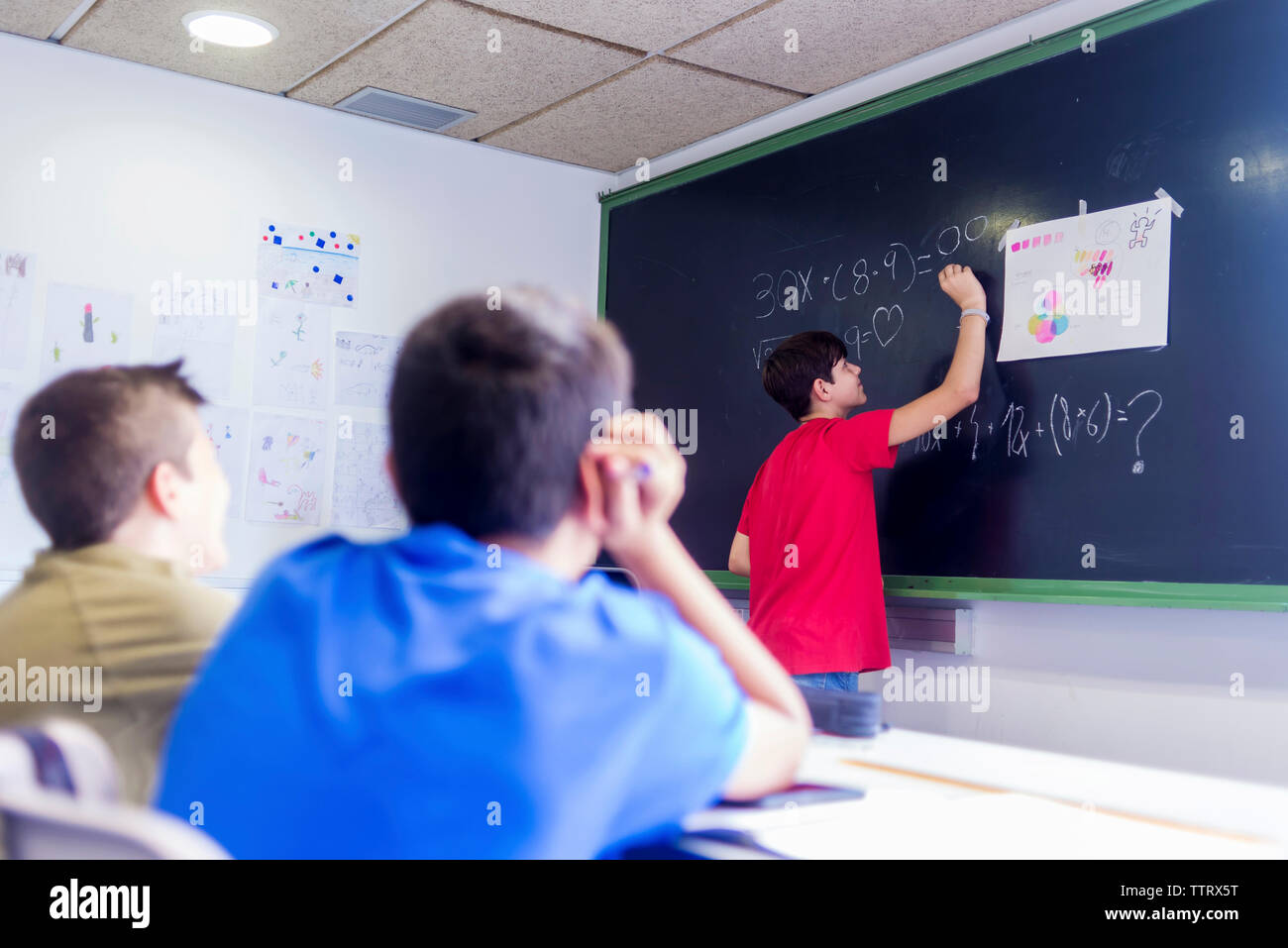 Ragazzo che spiega la matematica a maschio amici in aula Foto Stock