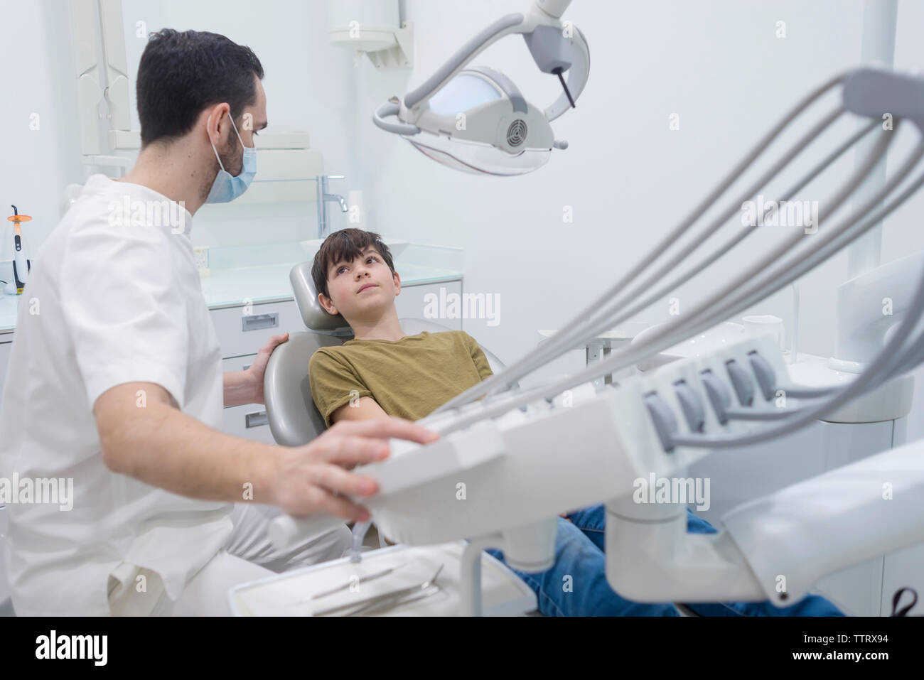 Dentista toccando macchinari mentre guardando il paziente in Clinica Medica Foto Stock